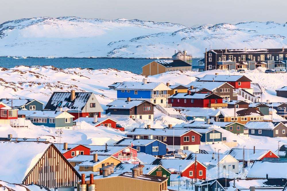 Colorful Arctic village with snow-covered houses, icy mountains - Greenland's arctic paradise awaits