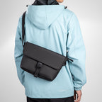 Black crossbody bag on model in light blue jacket - Mark Ryden Global travel essential