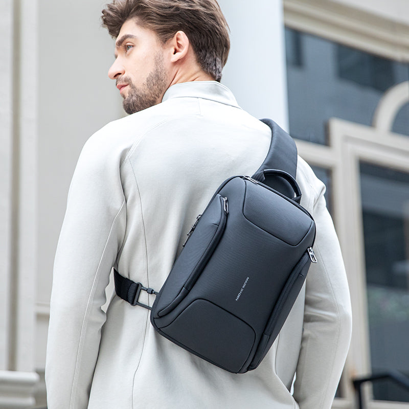 Dark gray Mini Polycom crossbody bag worn by man in light coat, modern city