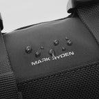 Black MotoBarrel cylinder crossbody bag with water-resistant fabric, water droplets beading, Mark Ryden logo visible