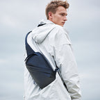 Dark blue simple clean waterproof large capacity crossbody bag by Mark Ryden, worn over a white jacket.