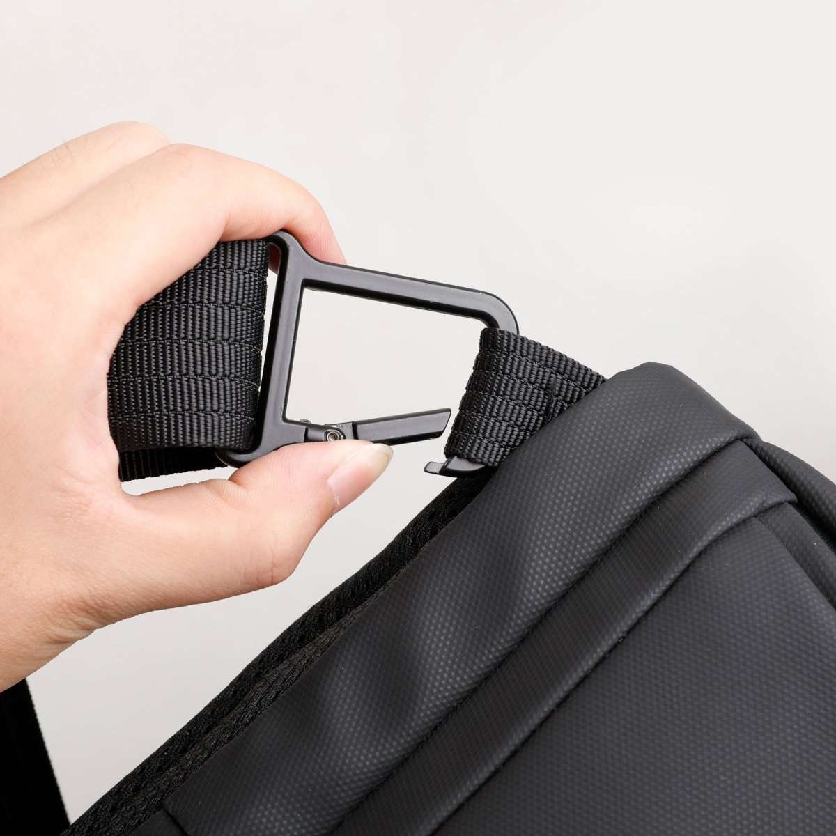 Close-up of black carabiner attached to textured strap of Mini Adventurer multifunctional sling bag with anti-theft pocket, designed for crossbody wear.