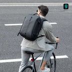 Man cycling with Mark Ryden black smart USB laptop backpack on city road