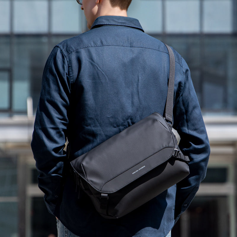 Black waterproof GameFlow sling bag for Nintendo Switch, 500g lightweight, worn by a person in a dark blue shirt in an urban setting.
