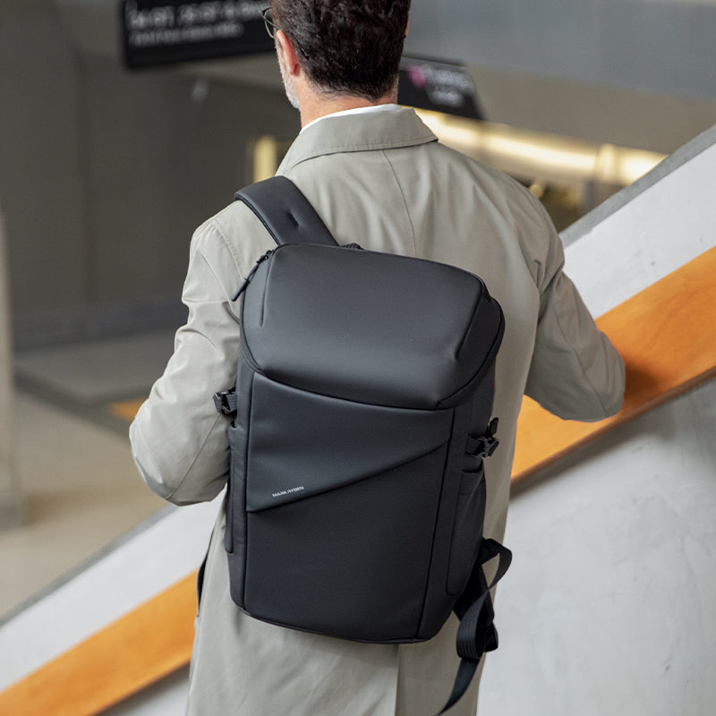 Mark Ryden AeroShield 2025 innovative black durable waterproof backpack with sleek structured design, worn by man in modern indoor setting.