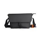 Black business casual travel crossbody bag with flap closure, adjustable straps, and orange accent detail.